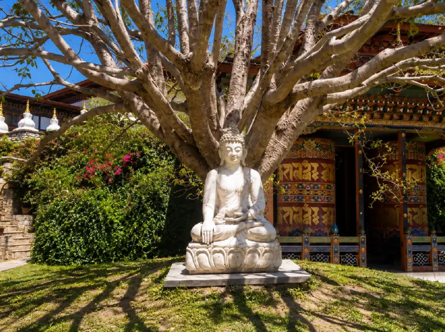 Buddha statue beneath a large tree at a traditional Buddhist temple in Bhutan